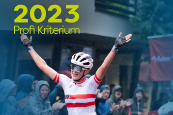 Weiblicher Rennradprofi feiert mit erhoben Armen ihren Sieg. Sie trägt rot-weißes Rennradtrikot.  &quot;2023 Profi Kriterium&quot; ist am Bild oben links in gelb/grün geschrieben. 