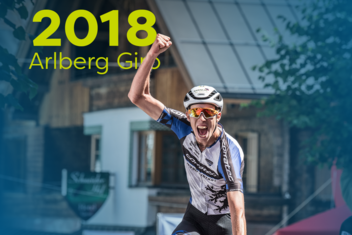 Racing cyclist cheers with a raised fist and is visibly shouting. ‘2018 Arlberg Giro’ is written in yellow/green at the top left of the picture.