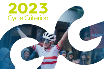 Female professional road cyclist celebrates her victory with arms raised. She is wearing a red and white racing jersey.  ‘2023 Cycle Criterium’ is written in yellow/green at the top left of the picture.