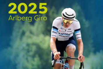 Rennradfahrer im Fokus konzentriert am Fahren, im Hintergrund sind grüne, üppige Wälder zu sehen. "2025 Arlberg Giro" ist am Bild oben links in gelb/grün geschrieben. 