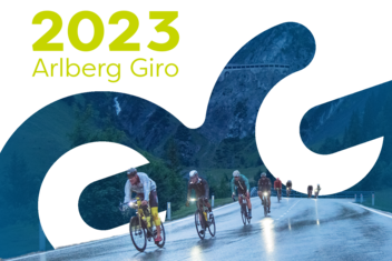 Four racing cyclists battle their way through the rain and mountainous landscape at the Arlberg Giro 2021. They are focussed and on the move. Female racing cyclist celebrates her victory with arms raised. She is wearing a red and white racing jersey.  ‘2023 Arlberg Giro’ is written in yellow/green at the top left of the picture.