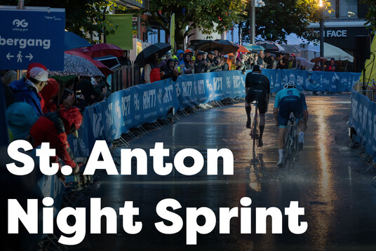 Sprintrennn bei Dämmerung und Regen durch die Fußgängerzone St. Antons mit jubelnden Fans.